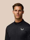 Front view of a man in a black Castore golf top with a winged logo on the chest and a center zipper