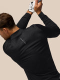 Close up of a golfer wearing a black Castore top with a vertical zipper gripping a golf club with a white glove