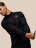 Side view of male model in black golf top with subtle print and Castore logo on chest