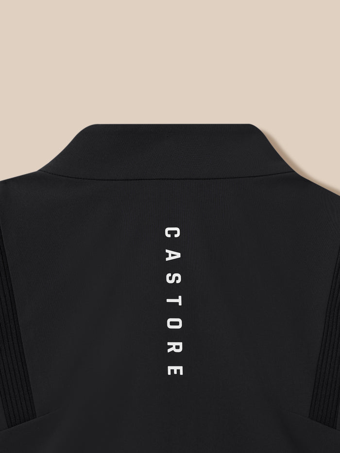 Back view close-up of the black Castore LVS winter jacket showing a curved collar against a beige backdrop.
