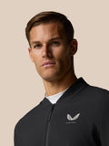 Male model wearing Castore Golf Pinnacle LVS Winter Jacket in black with front zip and left chest logo.