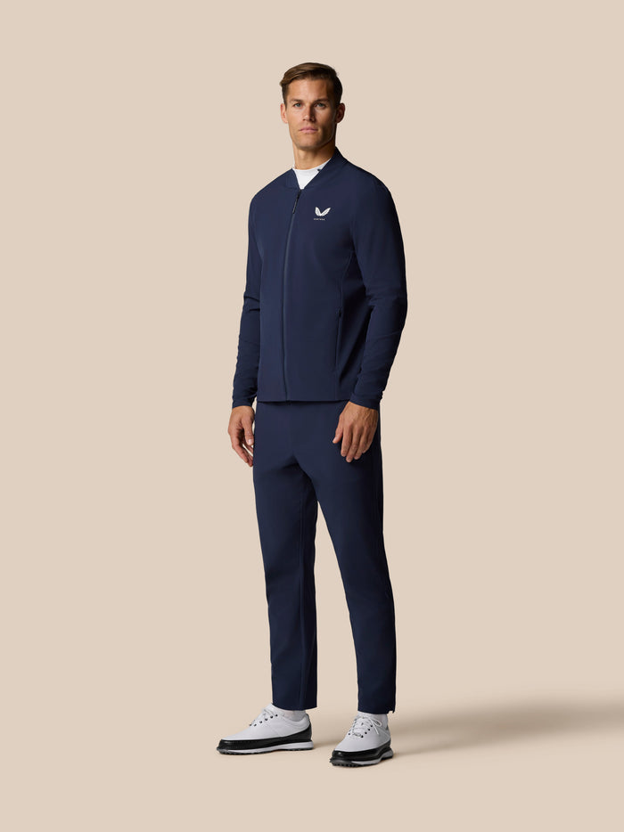 Male model wearing midnight navy Golf Pinnacle LVS Winter Jacket with full front zip and left chest Castore logo