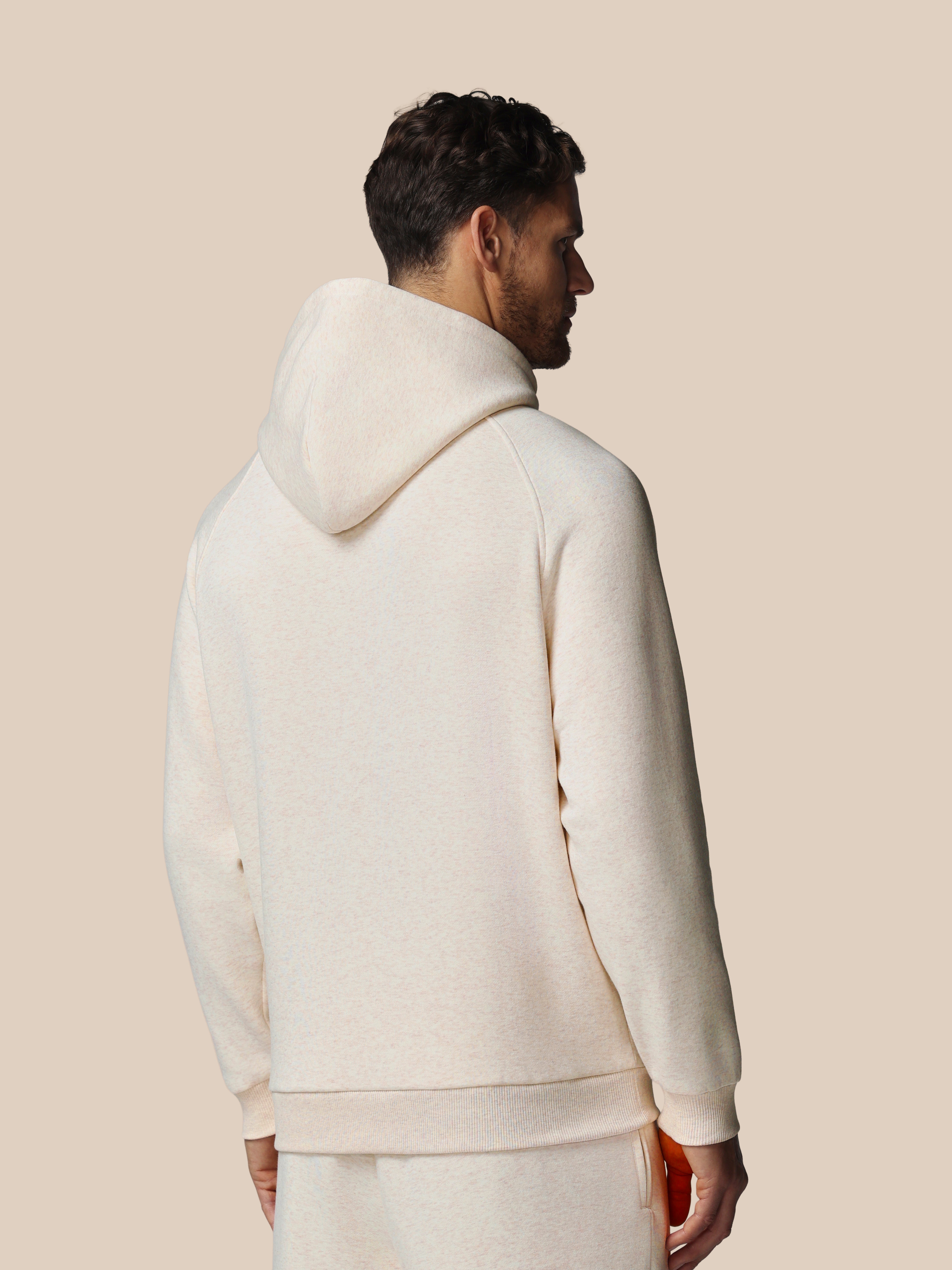 Man wearing a white hoodie and pants against a beige background