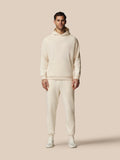 Man wearing a cream-colored hoodie and pants on a beige background