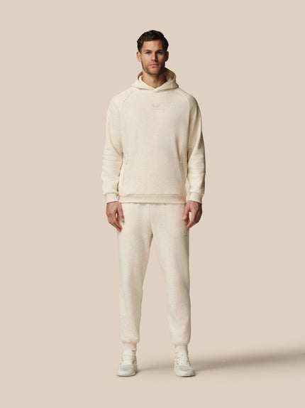 Man wearing a cream-colored hoodie and pants on a beige background
