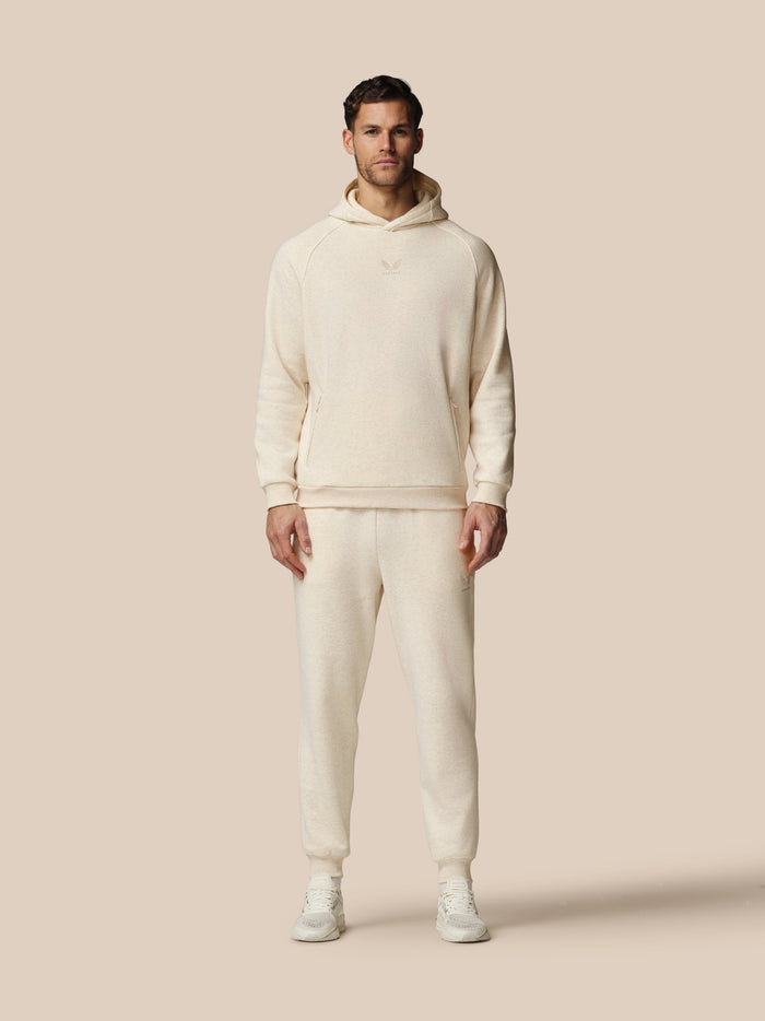 Man wearing a cream-colored hoodie and pants on a beige background