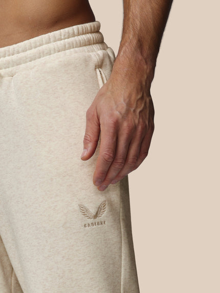 Beige sweatpants with a brand logo on a neutral background