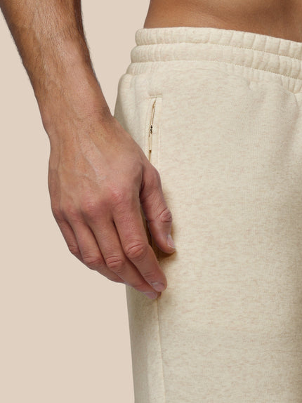 Close-up of a person wearing beige sweatpants with a neutral background