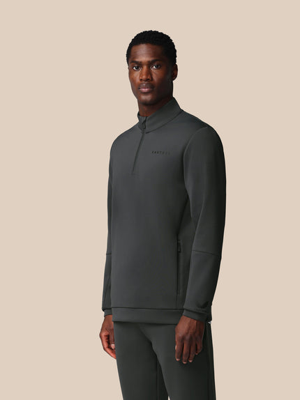 Man wearing a dark gray pullover with a brand logo on a beige background