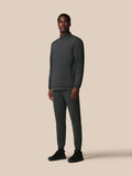 Man wearing a dark gray tracksuit on a beige background