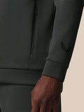 Close-up of a dark gray sweatshirt with a brand logo on the sleeve against a beige background