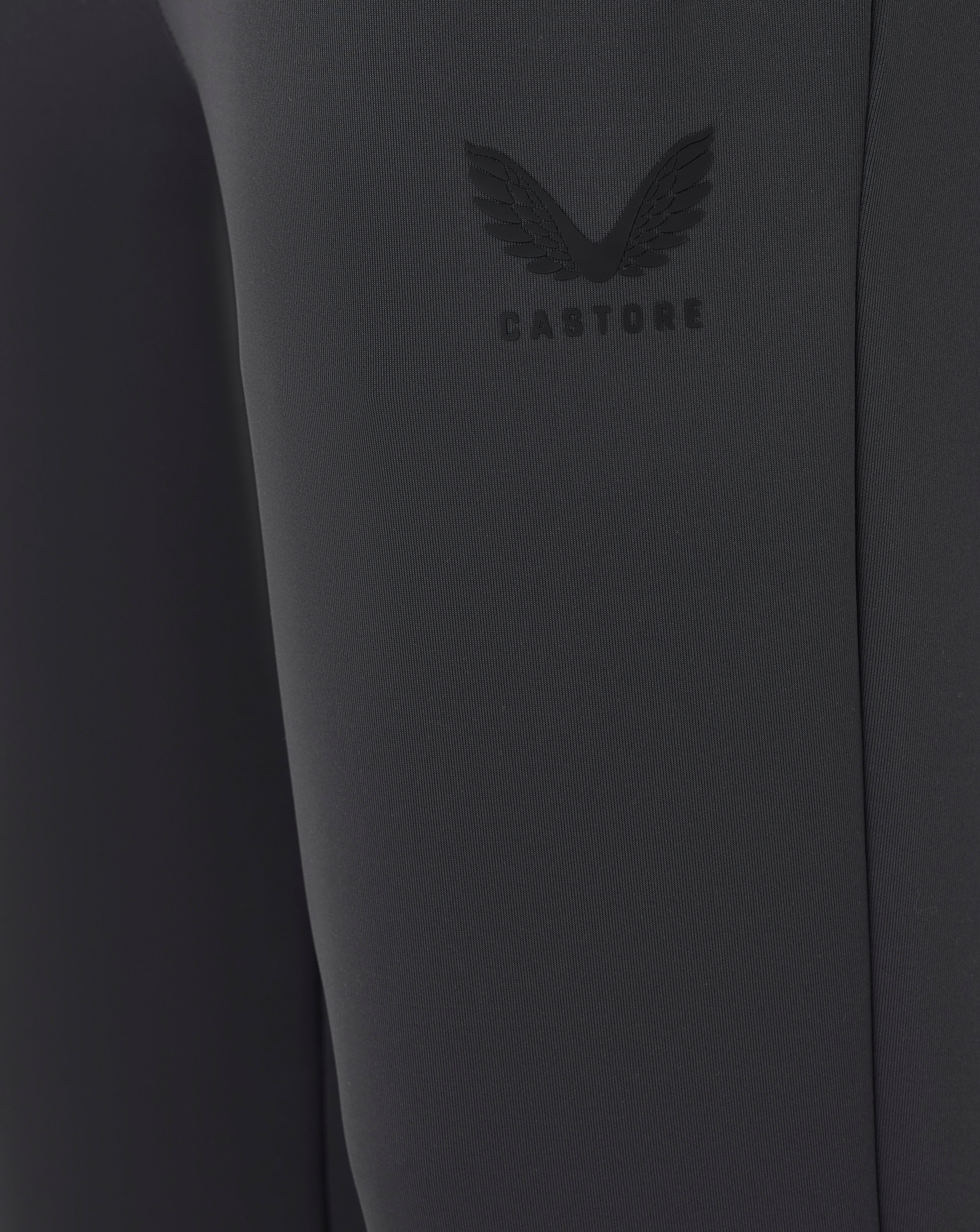 Close-up of a dark gray garment with a brand logo on a plain background