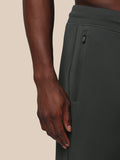 Person wearing dark green pants with a beige background