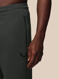 Person wearing dark gray pants with a brand logo on a beige background