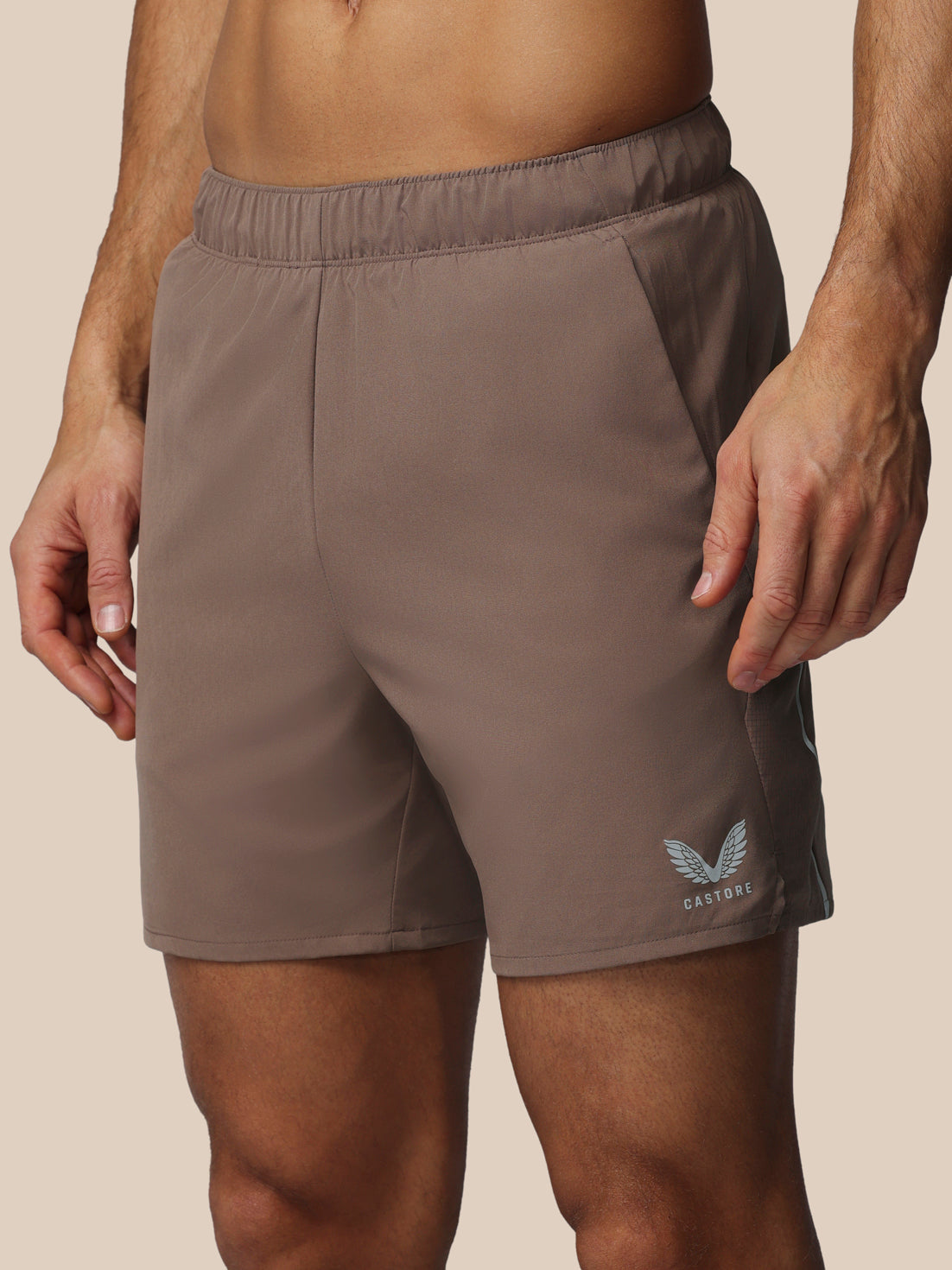 Brown athletic shorts with a logo on a beige background