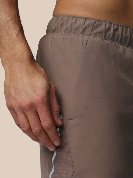 Close-up of a person wearing brown pants with a neutral background