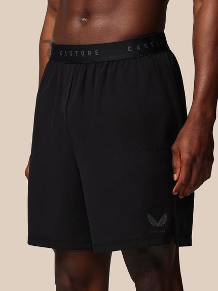 Black athletic shorts with 'CASTORE' branding on a beige background