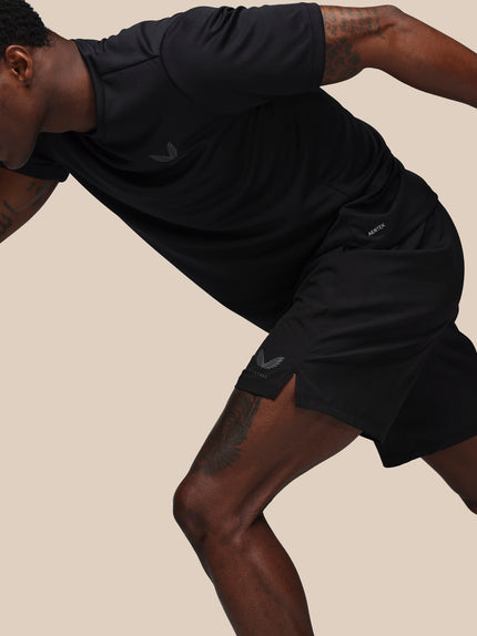 Person wearing black athletic shorts and shirt on a beige background