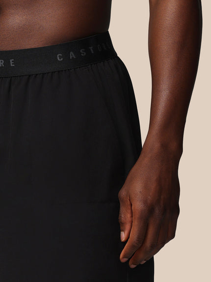 Black athletic shorts with a brand logo on a beige background