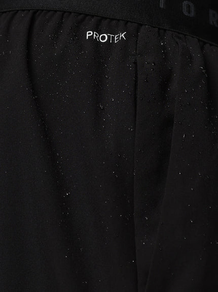 Close-up of a black jacket with 'PROTEK' branding on a dark background