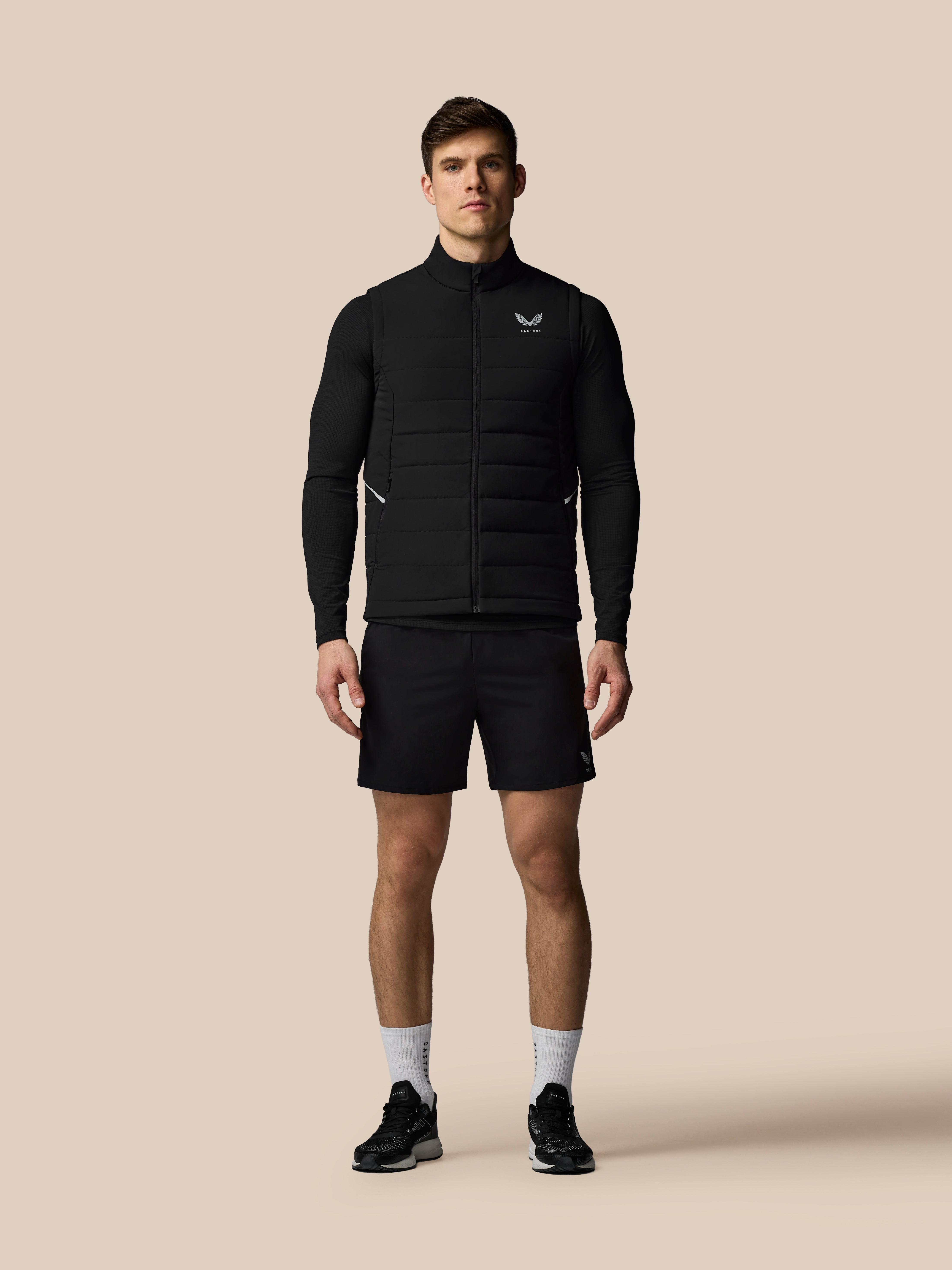 Man wearing a black jacket and shorts on a beige background