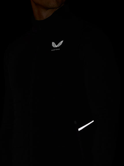 Black hoodie with a logo on the chest and reflective strip on the sleeve against a dark background