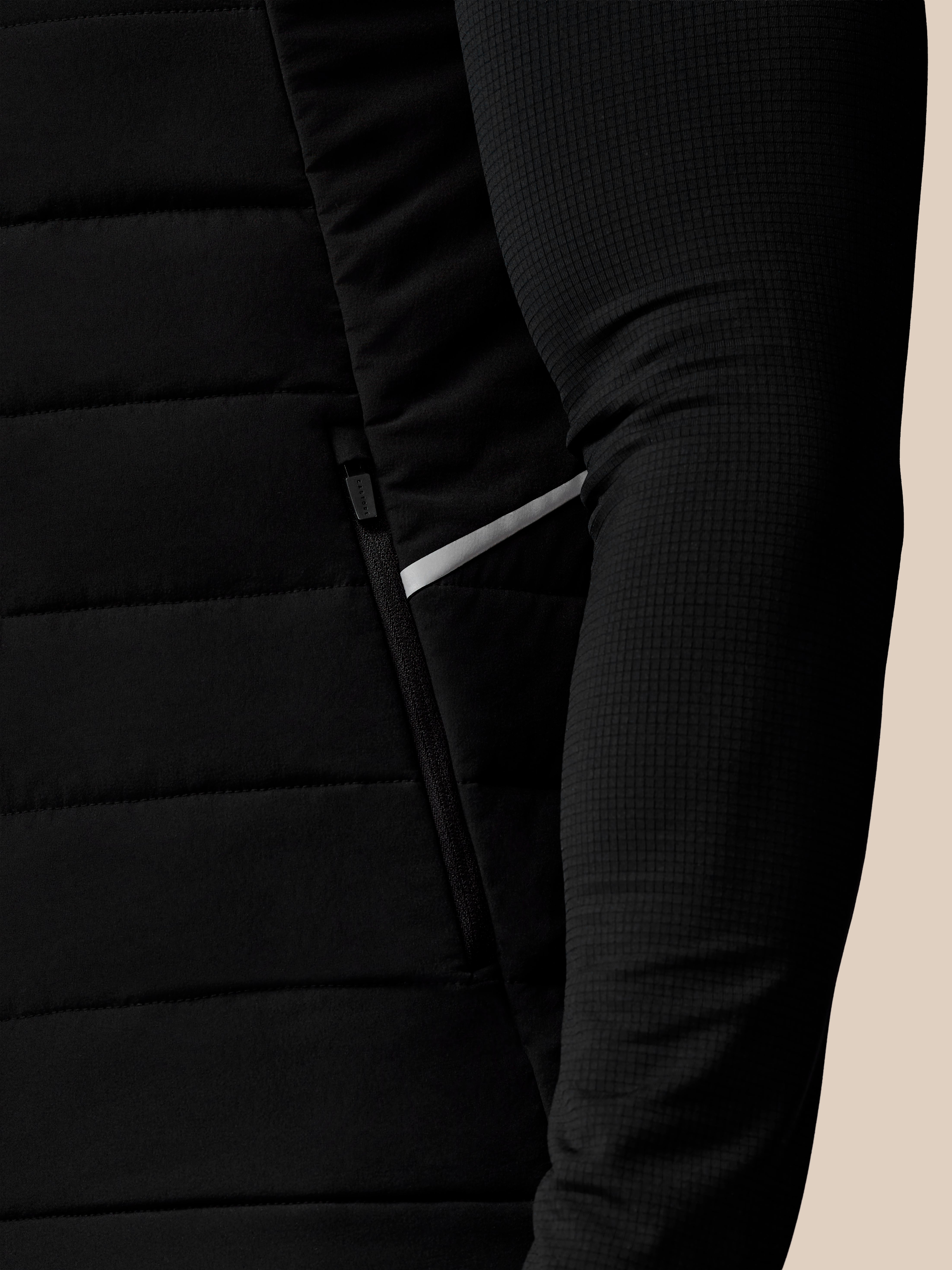 Close-up of a black puffer jacket with a beige background