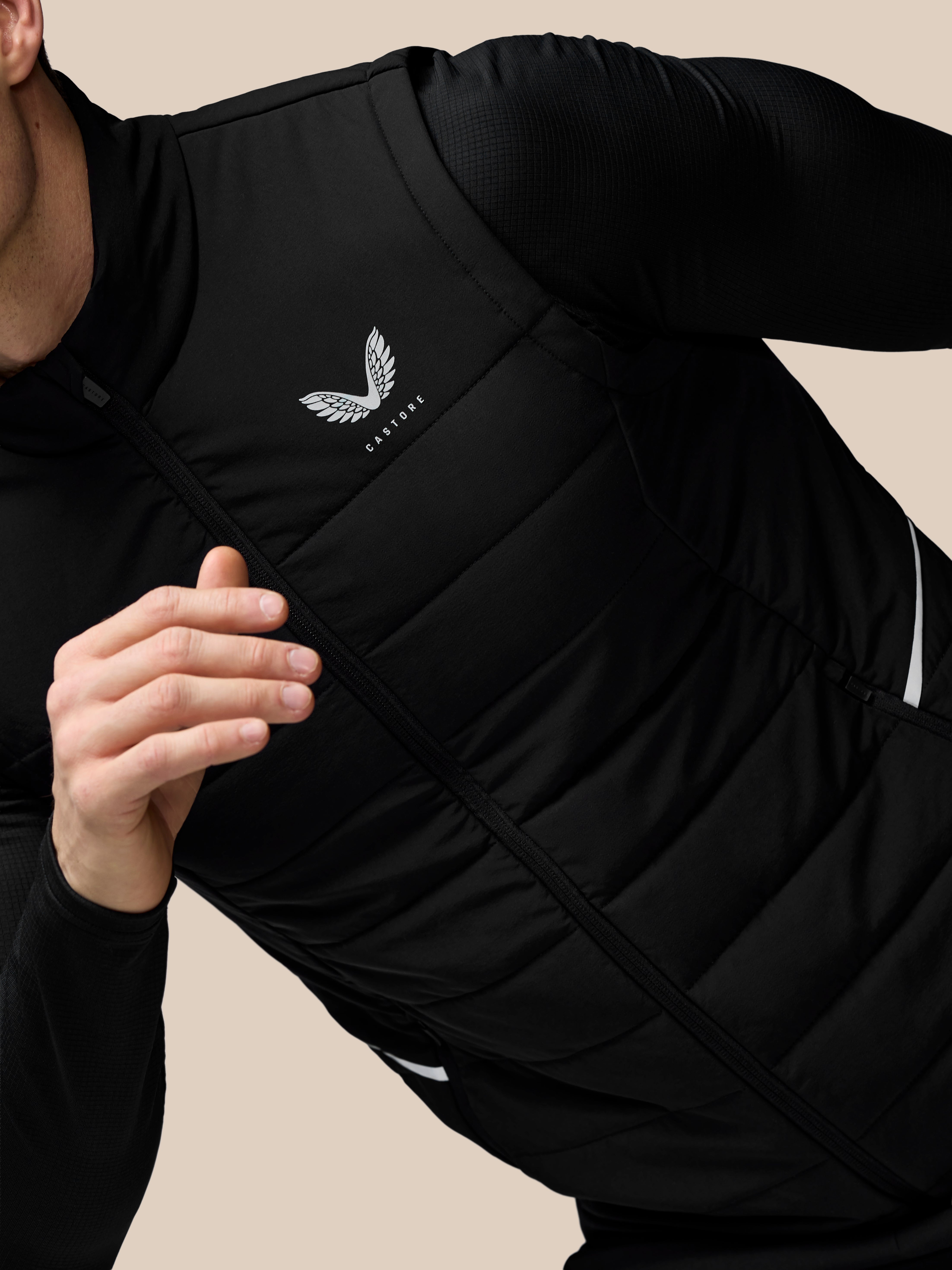 Person wearing a black jacket with a logo on a beige background