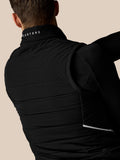 Person wearing a black puffer jacket with 'Castore' branding on a beige background