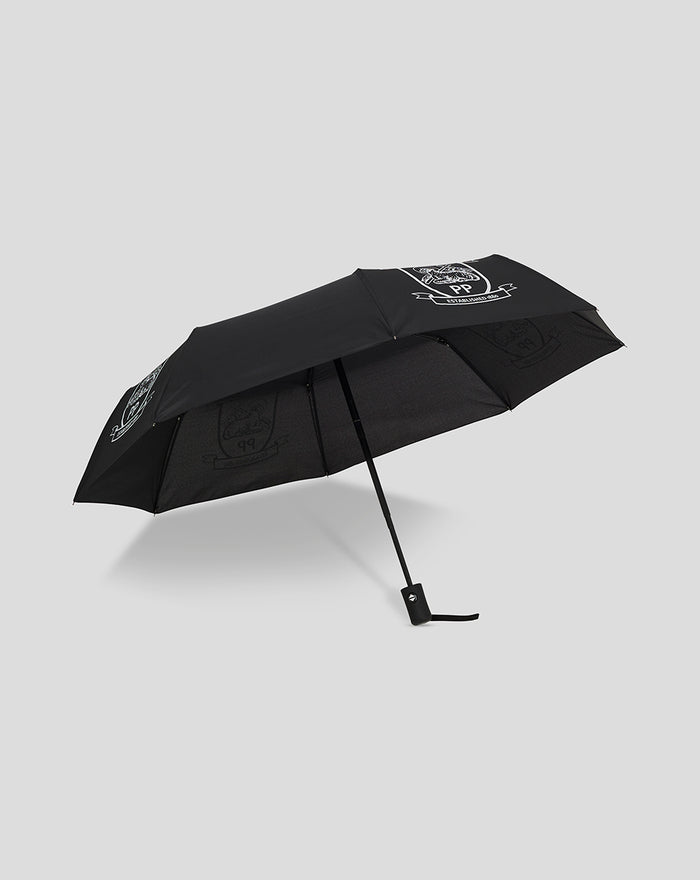 Open black telescopic umbrella with white crest graphics and a wrist strap against a light background