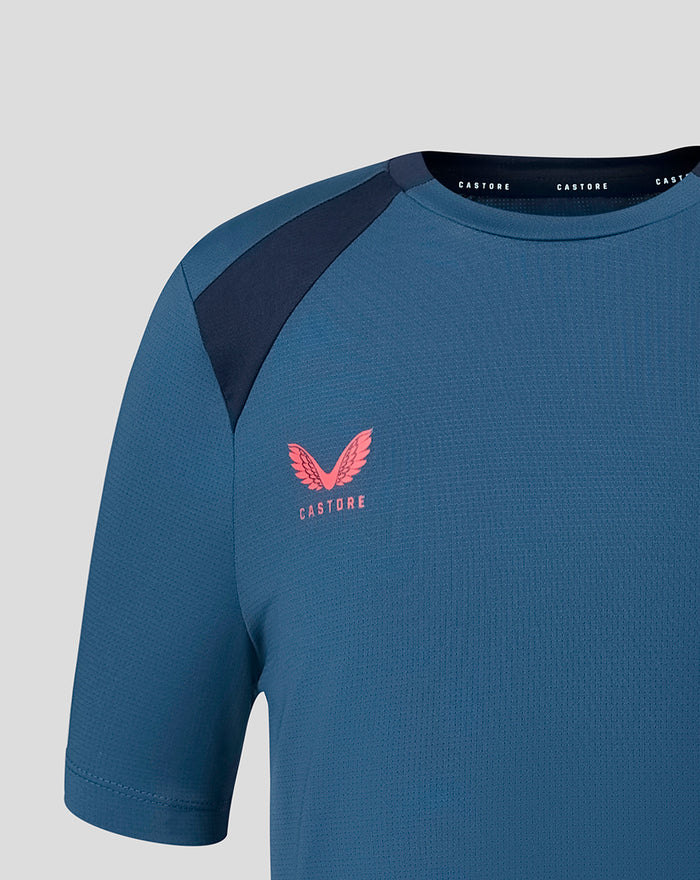 Close up of blue training tee showing navy shoulder panel and pink crest on left chest