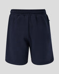 Back view of navy travel fleece shorts with a coral logo at the left leg hem.