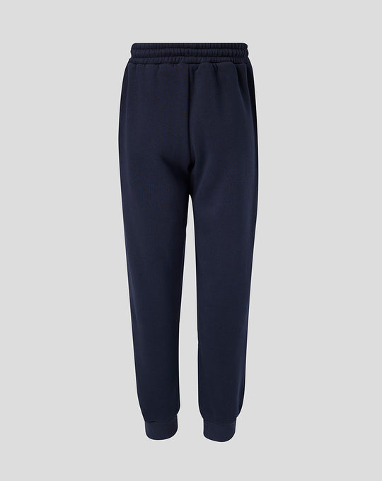 Full-length navy Travel Adapt fleece joggers with drawstring waist, crest on the left thigh and coral branding on the right.