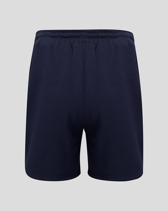 Back view of navy fleece shorts with elastic waistband and small coral crest near the hem.