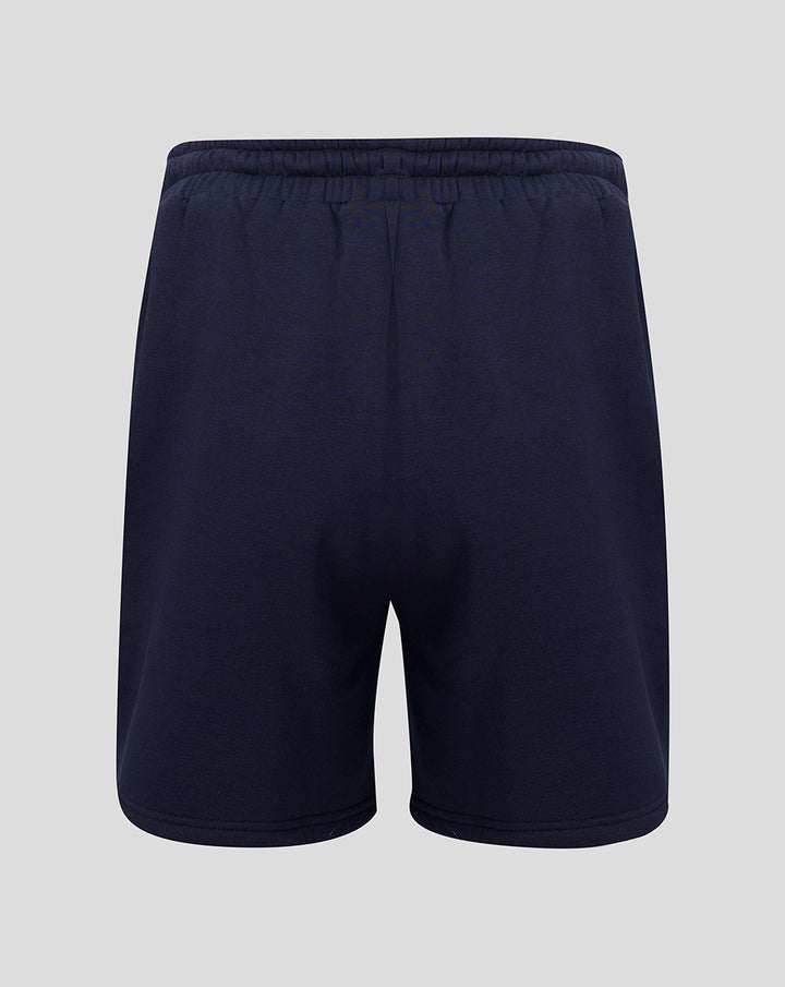 Back view of navy fleece shorts with elastic waistband and small coral crest near the hem.