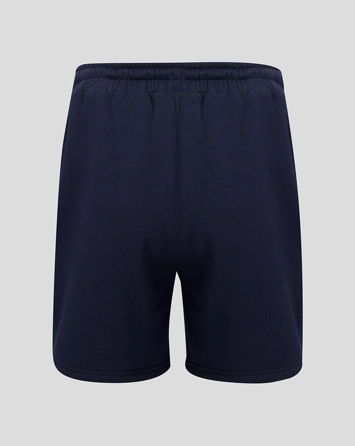 Back view of navy fleece shorts with elastic waistband and small coral crest near the hem.
