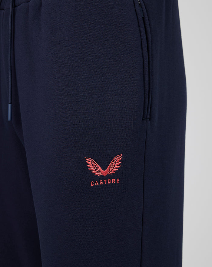 Navy travel fleece jogger close up with coral Castore logo near the pocket.