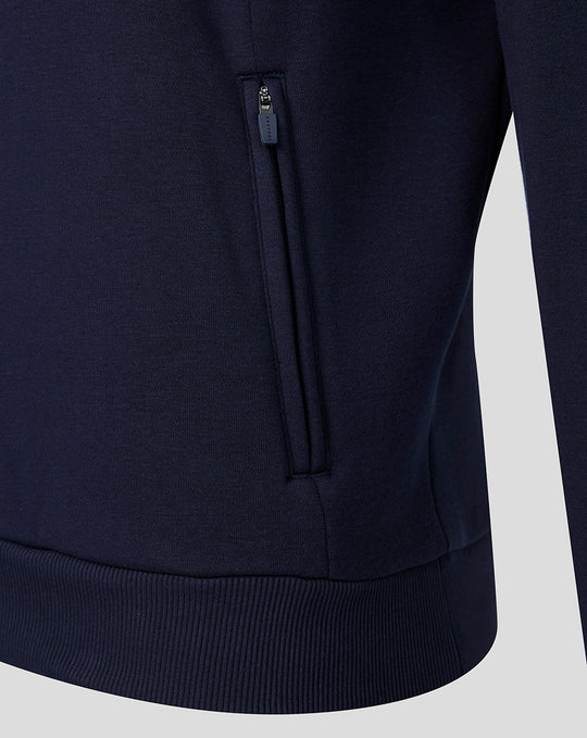 Navy fleece hoodie close-up showing a zippered side pocket and ribbed hem.