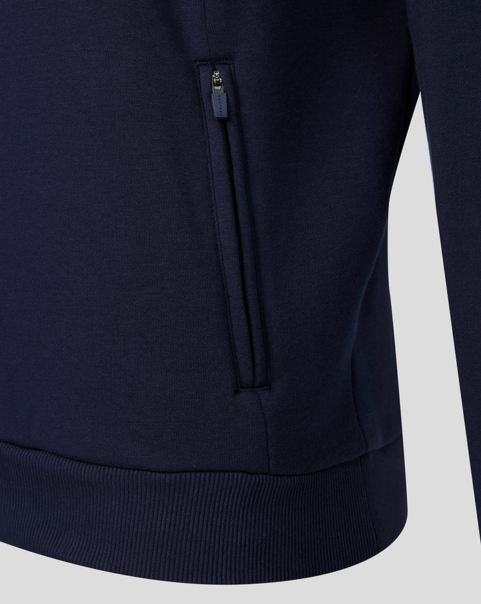 Navy fleece hoodie close-up showing a zippered side pocket and ribbed hem.