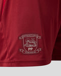 Close-up of red shorts fabric with white Preston North End FC crest embroidery near the hem