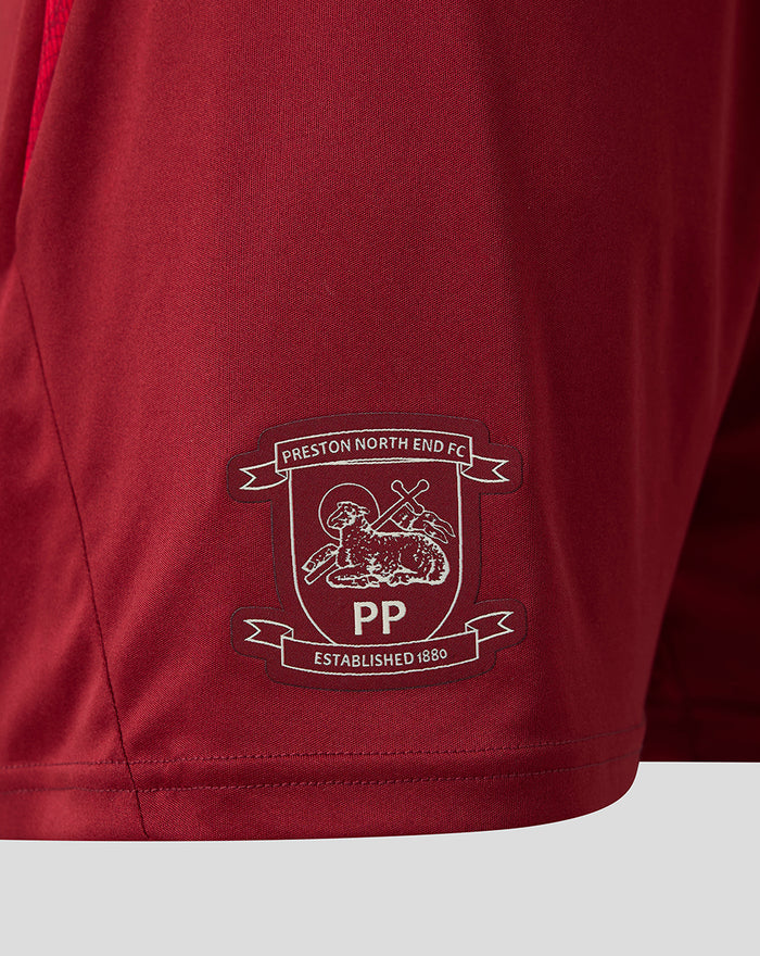 Close-up of red shorts fabric with white Preston North End FC crest embroidery near the hem