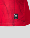Red fabric with a small black Castore authenticity patch near the bottom hem