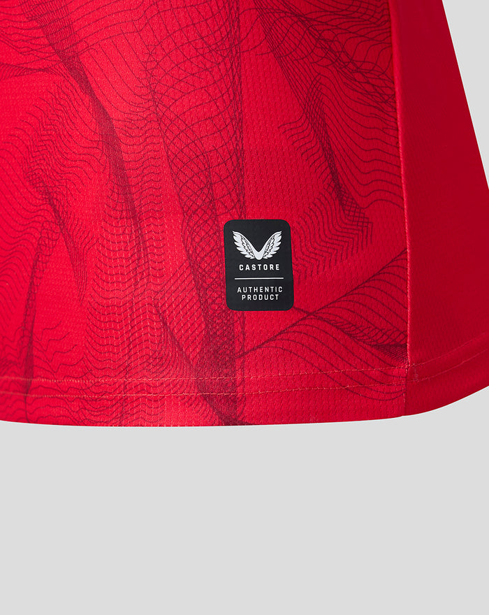 Red fabric with a small black Castore authenticity patch near the bottom hem