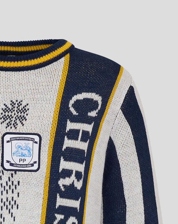 Close up of junior Christmas jumper knit in cream and navy with a yellow striped crew neck and crest patch on the chest.