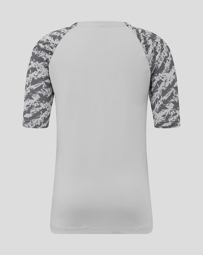 Back view of grey junior training tee with camo patterned sleeves.