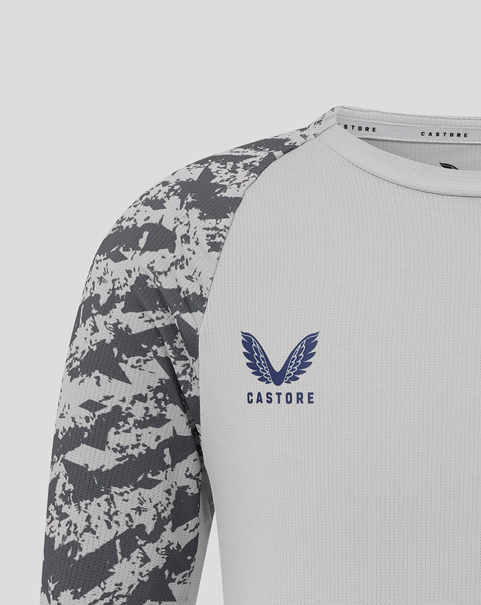Close-up of chest showing Castore crest and winged logo on light grey training tee with camo sleeves.