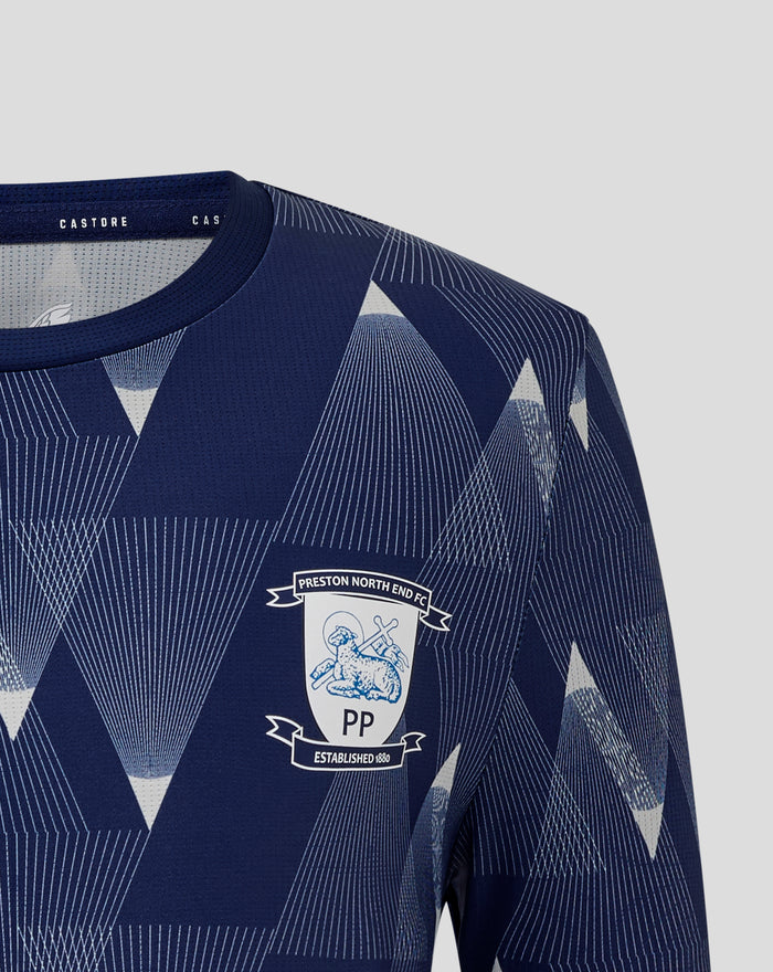 Close-up of the navy junior matchday shirt collar and shoulder showing the geometric pattern and partial club crest