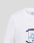 Close up of white fabric displaying part of the crest emblem on the chest.