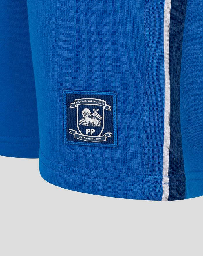 Back view of blue junior shorts featuring a crest patch and white side stripe