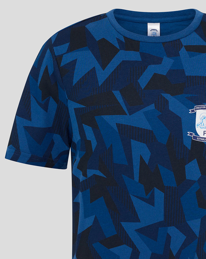 Close-up of blue geometric print tee with crest patch on chest.